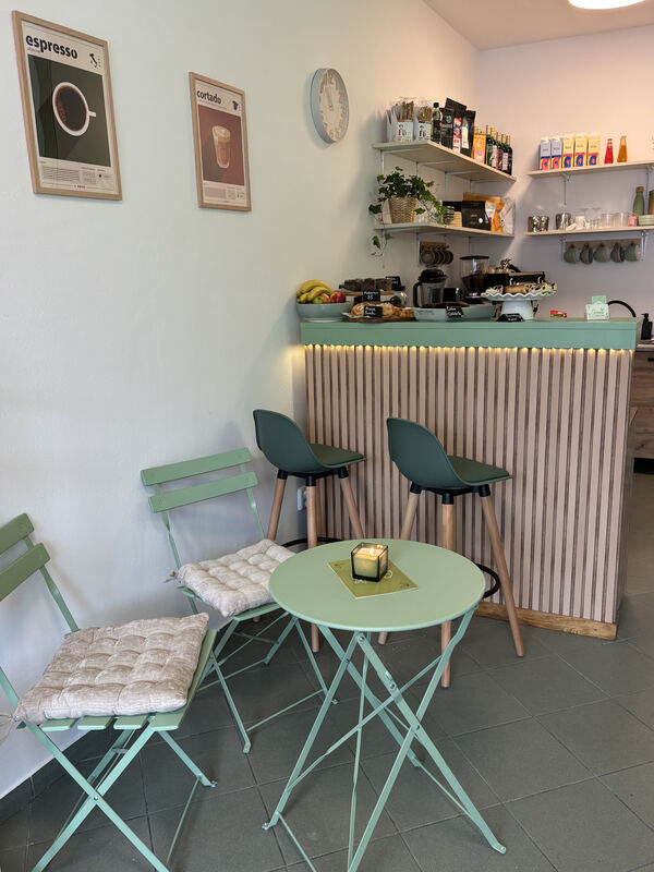 Interiér Greens — bar, vysoké židle a stolky u okna